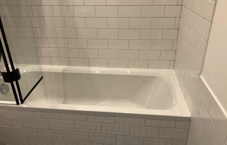 Bathtub with white wall tiling in Lewisham