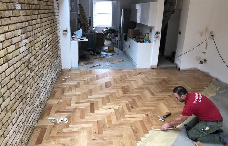 Parquet floor laying next to the exposed brick wall in Lewisham
