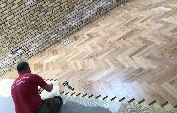 Fitting herringbone wood flooring in living area in Lewisham
